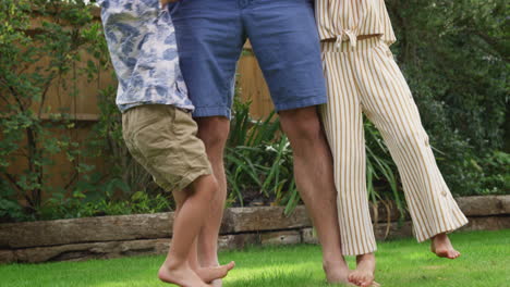 asian father with children having fun playing as they walk on his feet in garden at home