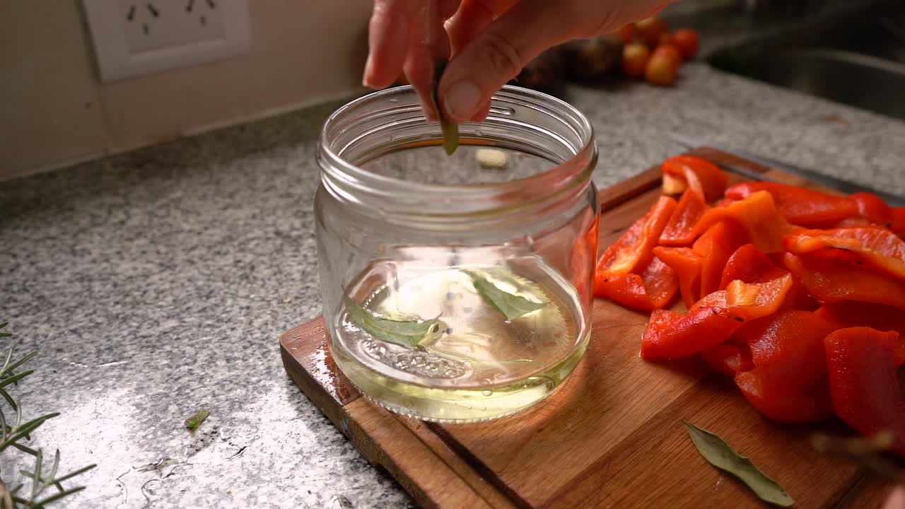Adding Bay Leaves Into Jar With Sunflower Oil, Water, And Black Peppercorns