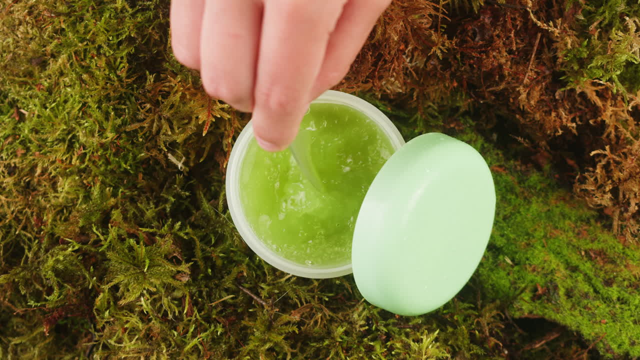 Bottle of cosmetics cream serum on moss forest background green leaves. Woman Make up healthy natural products.