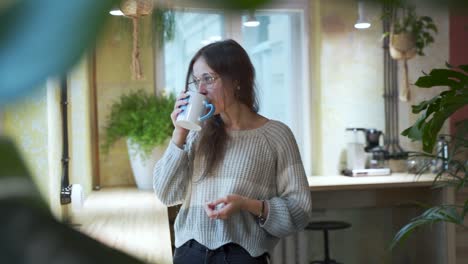 젊은 유럽 여학생이 자연 배경을 가진 커피숍에서 커피나 차를 마시고 있다