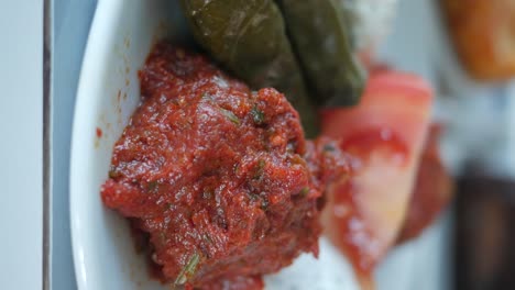 close-up of a vibrant red food dish, possibly a spicy dip or spread, served on a white plate