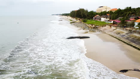 Rapidly-decreasing-beach-of-Vietnam-in-Mui-Ne-due-to-global-warming-crisis-in-world,-aerial-fly-over-view