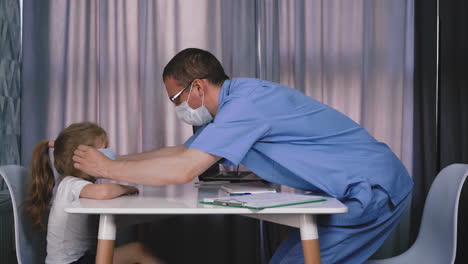 doctor in glasses puts mask on little cute girl in hospital