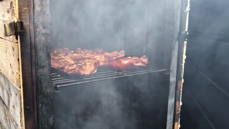 juicy meat grilling in a large barbecue, smoke billowing as the door is opened