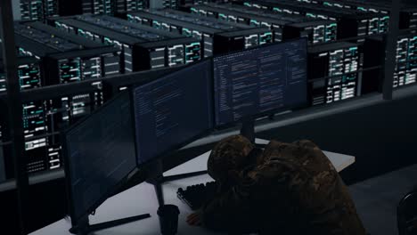 vista lateral de un militar asiático cansado durmiendo mientras escribe código con múltiples pantallas de computadora en el centro de datos