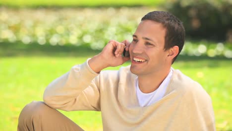 Young-man-phoning-sitting-on-the-grass