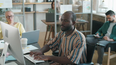 black businessman with disability typing on computer in office