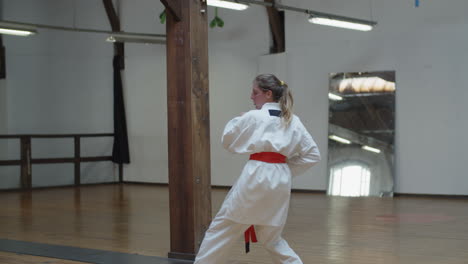 tiro de seguimiento de chica enfocada en kimono practicando karate en el gimnasio