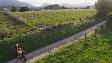 groupe de trois jeunes pèlerins marchant ensemble sur un chemin de terre par un jour d'été venteux