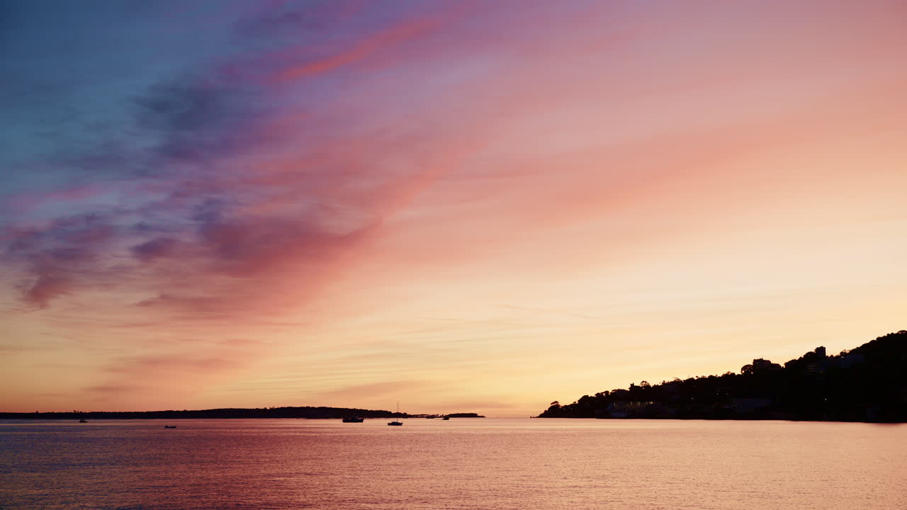 Beautiful sunset sky in warm shades of orange, pink, and purple above a calm coastline in the French Riviera