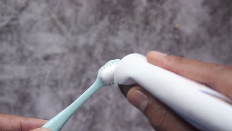 applying toothpaste to a toothbrush