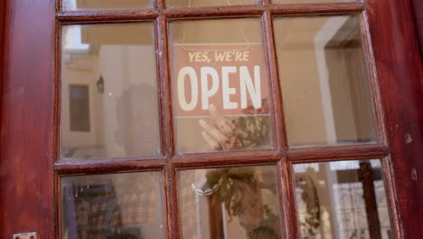 African-american-male-business-owner-changing-shop-sign-to-open,-slow-motion