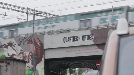 Train-passing-over-bridge-decorated-in-graffiti,-Milan-city-suburbs