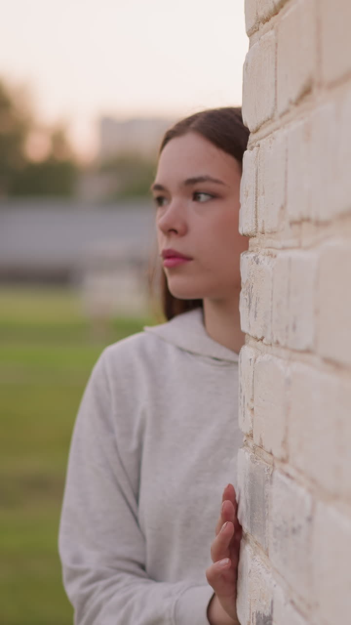una mujer sale de la pared de graffiti del edificio del estadio. una mujer joven tiene miedo de conocer a la gente mientras está deprimida. buscando un lugar aislado para escapar