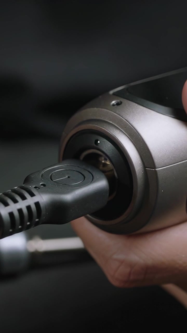 Vertical video: Connecting hands inserting plug into device close-up for charging, blue LED glowing