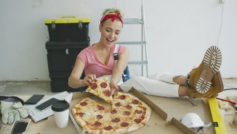 woman in overalls eating pizza at workplace