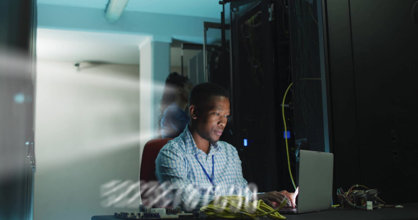 IT tech typing on laptop in data center, causing numeric overlays arcing while monitoring network