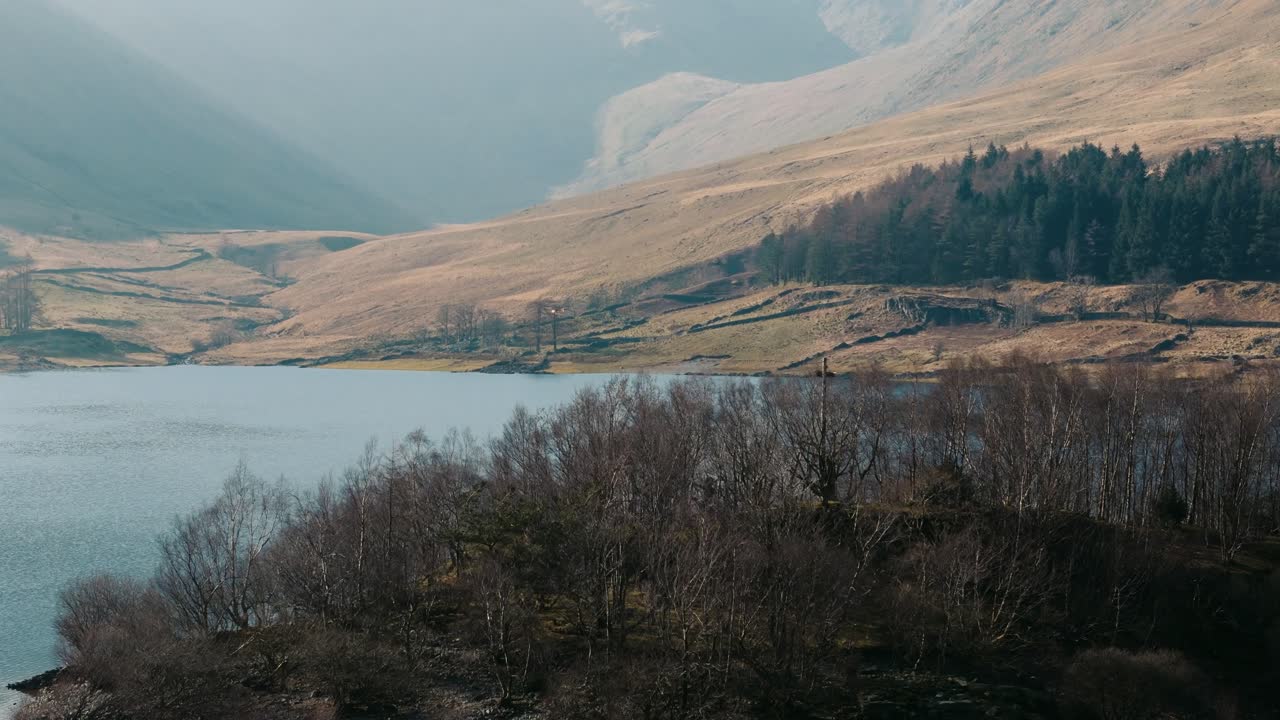 Smooth aerial flyover of small island on calm Lake District lake
