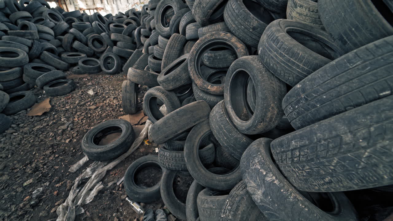 Lot of old tires from cars. Second hand tyres stacked up at old dump