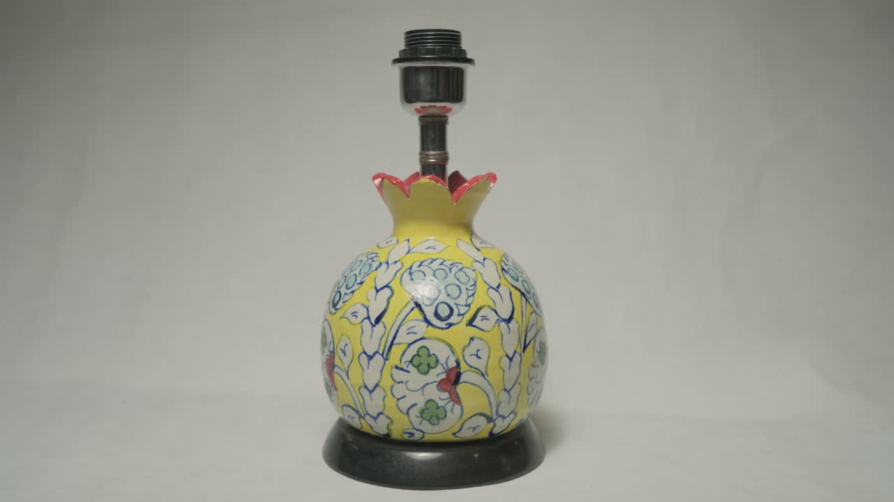 Closeup view of ceramic lamp base adorned with blue white and red floral design on it. Clay pottery.