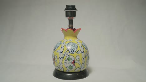 closeup view of ceramic lamp base adorned with blue white and red floral design on it. clay pottery.