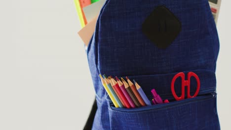 video de mochila con lápices de colores, reglas y tijeras sobre fondo beige