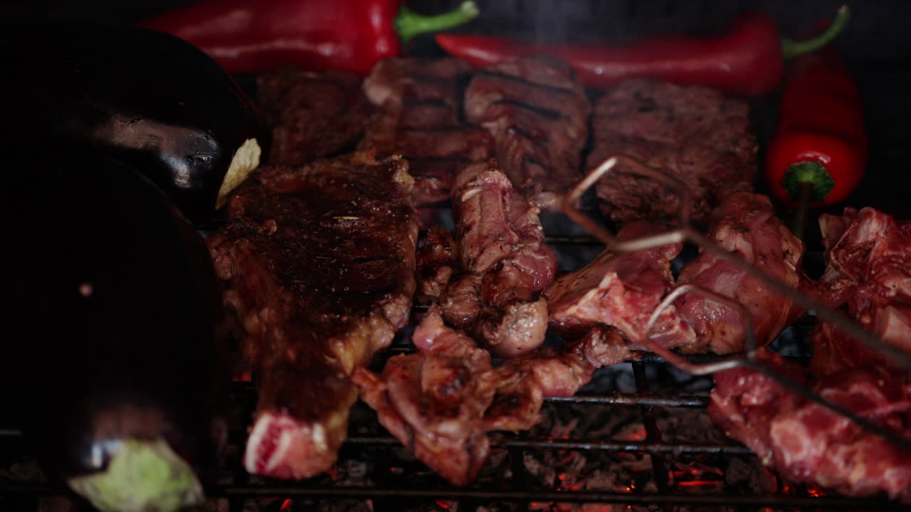 Daging panggang dengan bekas panggangan terlihat jelas sedang dibalik saat dimasak di atas bara api panas bersama sayuran.