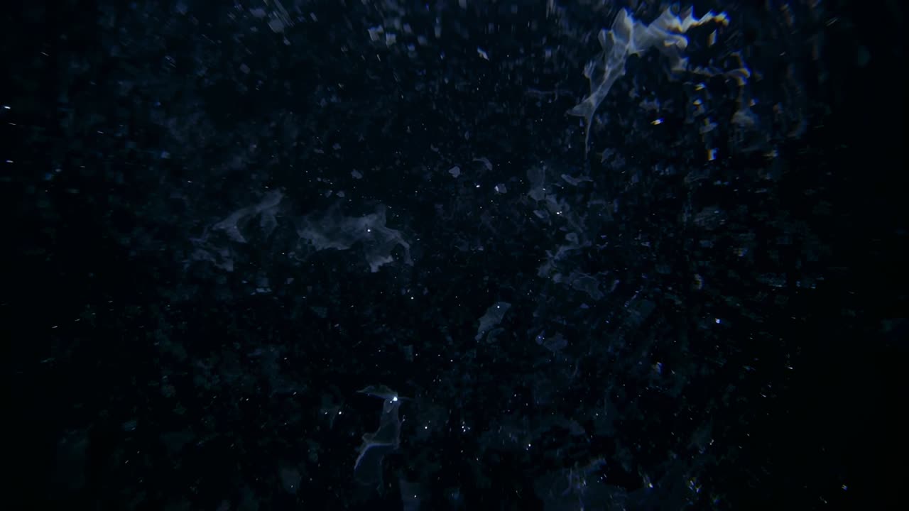 Rising turbid water column being pushed by bubbles and revealing particles in tank, overhead light