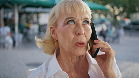 retired lady talking cellphone on street close up. portrait of old woman calling