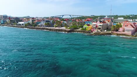 drone ascends clear caribbean waters and waves crashing on coast of punda willemstad curacao