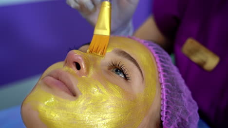 woman getting facial nourishing mask by beautician at spa salon. apply face mask, spa beauty treatment and skincare.
