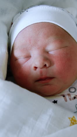 adorable sleeping infant child in cap and covered in blankets. newborn baby close up. yellow backdrop. vertical video