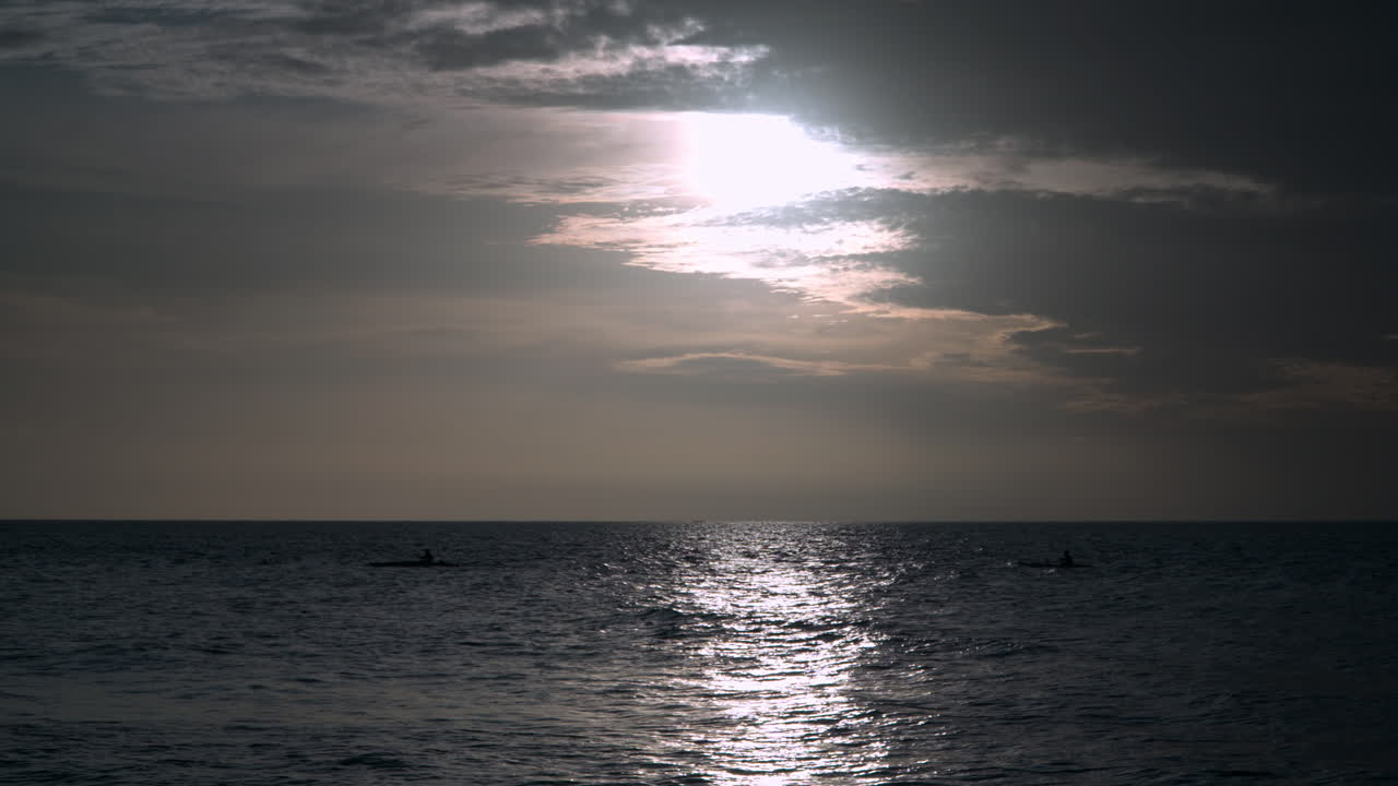 말레이시아 코타키나발루 탄중아루 해변 근처에서 해질녘 바다에서 패들보드를 타는 사람들