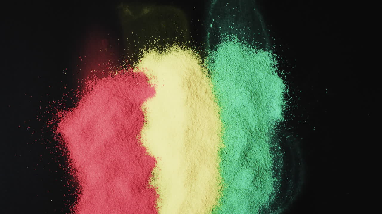 Video of red, yellow and green powders with copy space on black background