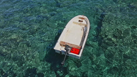 empty small boat moored and floating at crystal clear blue water on a sunny day