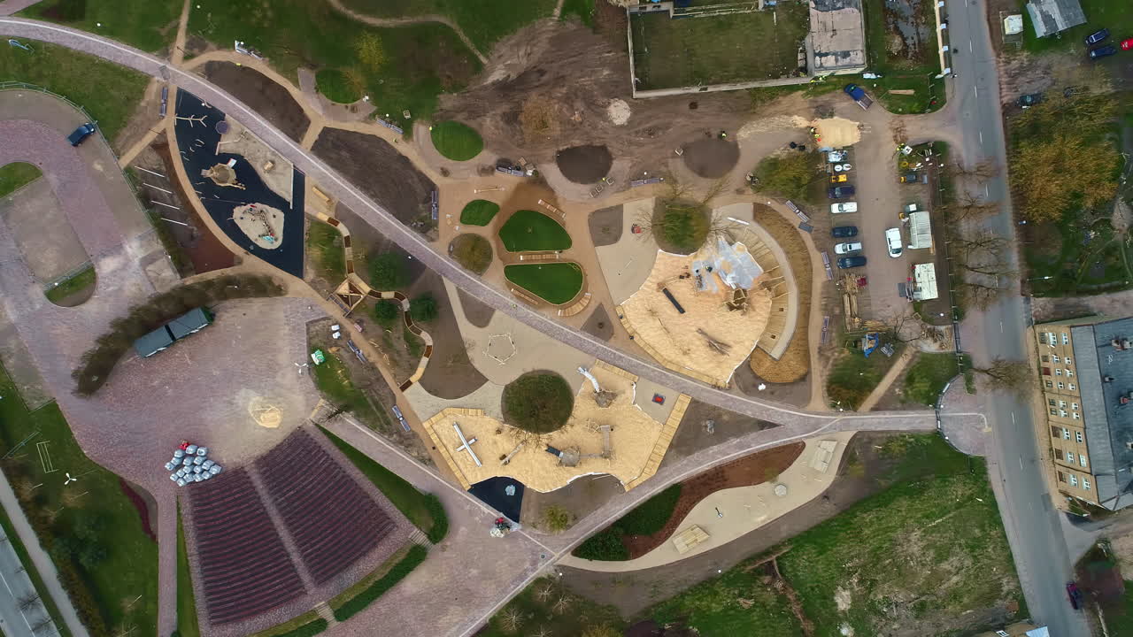 воздушный дрон сверху вниз перекрестные сельские дороги вокруг сельскохозяйственных полей геометрические формы осенней зеленой травы и коричневой крыши, осенняя архитектура