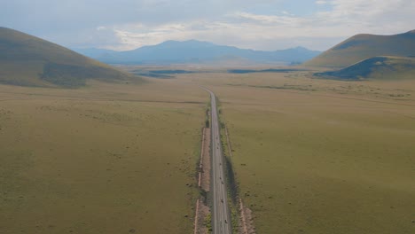 An-aerial-nose-down-shot-that-tilts-up-of-a-group-of-motorcycles-riding-down-a-backroad-in-Arizona-that-reveals-a-mountain-range-ahead