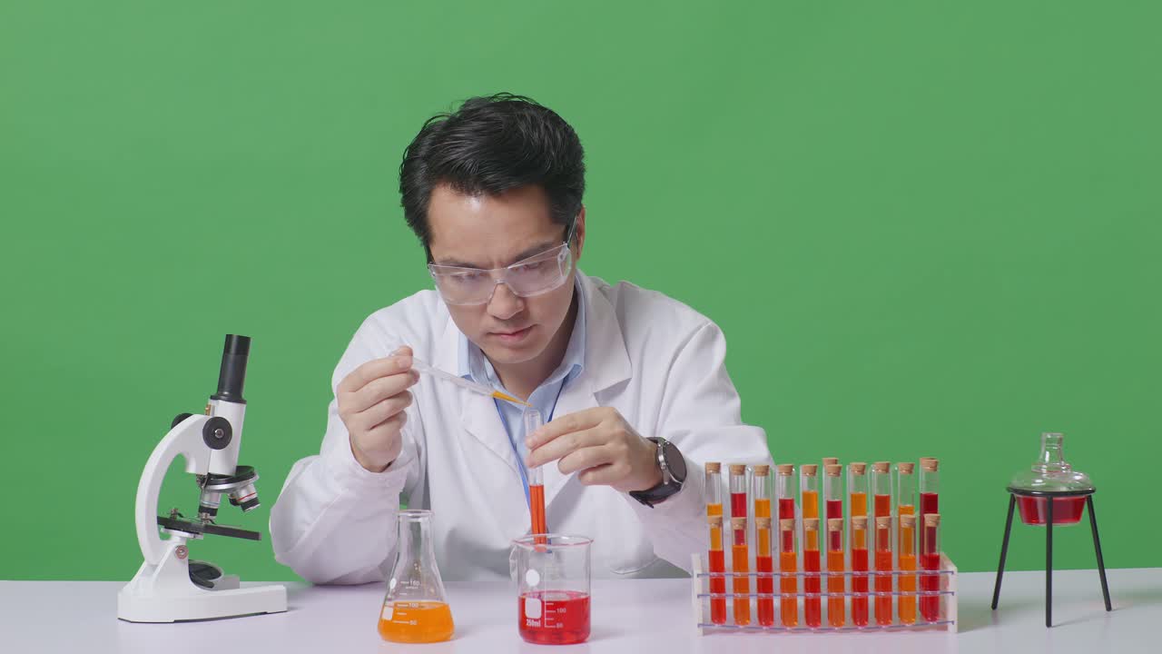 Asian Man Scientist Making Experiment With Test Tube And Saying Wow While Working On The Table With Microscope In The Green Screen Background Laboratory