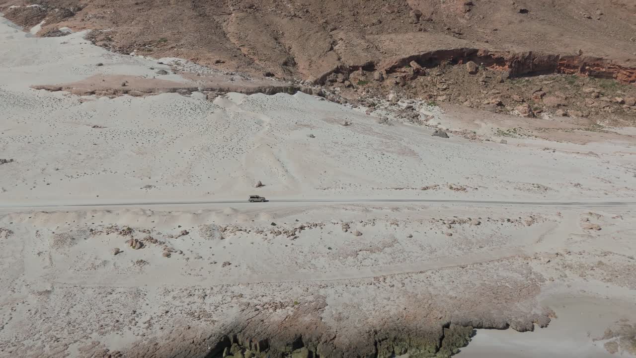 Car driving on a desert road through an arid landscape