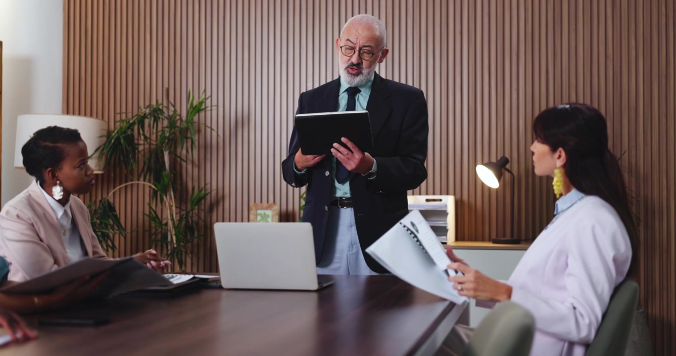 Uomo d'Affari Senior che Presenta Dati ai Colleghi in un Ufficio Moderno