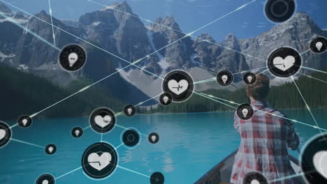 Animation-of-network-of-connections-with-icons-over-caucasian-man-in-boat-on-lake-in-mountains