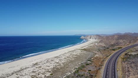 Imágenes-De-Drones-De-Cabo-San-Lucas-Y-Todos-Santos-Road-En-Baja-California-Sur-México,-Con-Aguas-Cristalinas-Del-Océano-Azul-Y-Montañas-En-La-Distancia