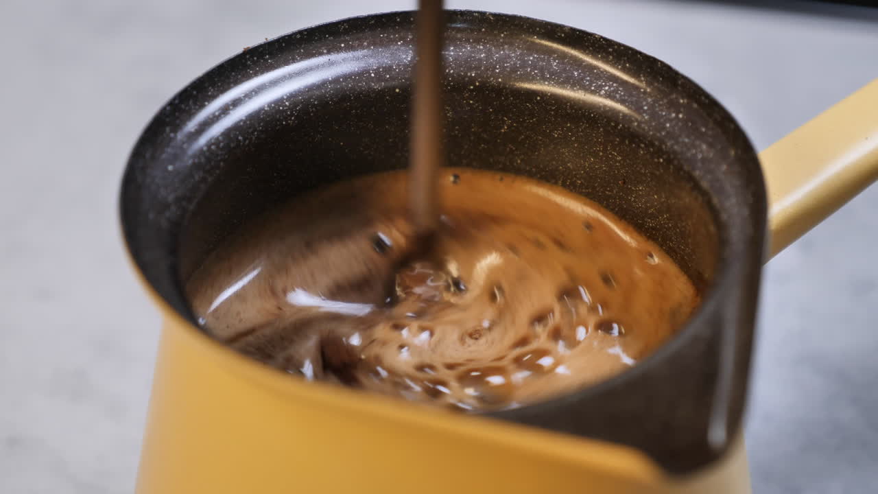 agitar café fresco con una cuchara en la cafetera después de agregar granos de café mezclados frescos