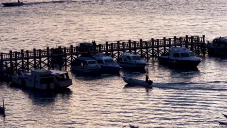pescador solitario en lancha motora al atardecer que llega al muelle para amarrar en el pueblo pesquero de labuan bajo en la isla de flores, región de nusa tenggara en el este de indonesia