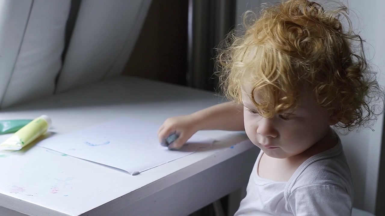 Toddler painting with mommy and coloring with a potato in front of living room window.