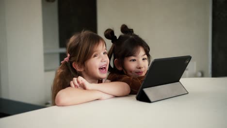 two diverse sisters using the tablet digital computer for e-learning or watching cartoons