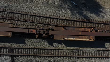 vista de arriba hacia abajo de vagones de tren oxidados moviéndose a lo largo de un conjunto de vías en un día soleado por la mañana