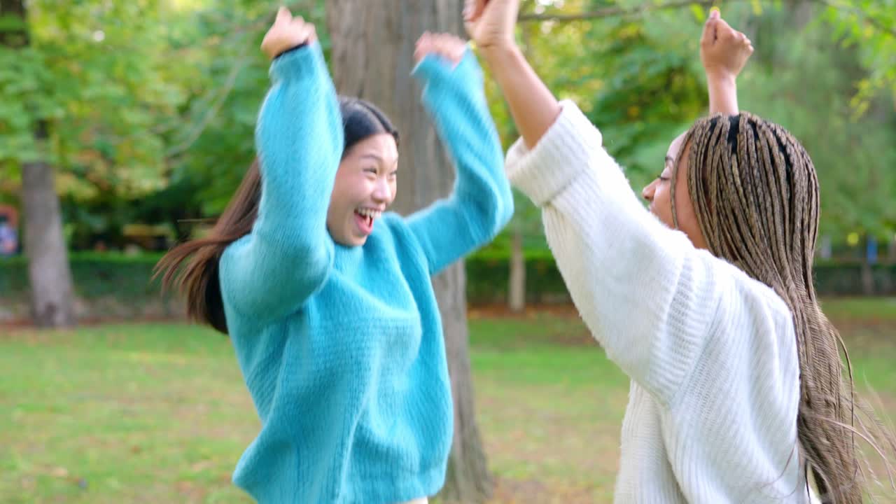 Two young women embracing happily in a park