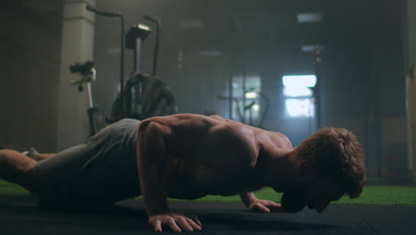 a strong man performs push-ups from the floor with all his strength. a pumped-up man does push-ups in the gym