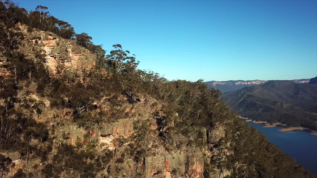 antena: rastreo de drones alrededor de una montaña para revelar un hermoso lago azul en nueva gales del sur, australia